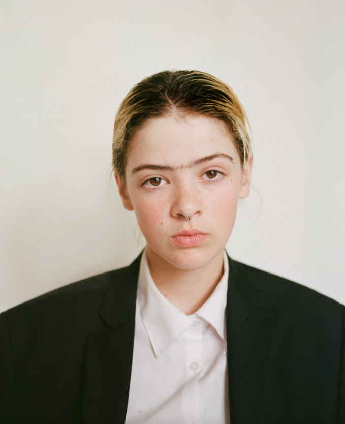 Photograph by Xanthe Hutchinson of her son in the process of transitioning, wearing a suit and a monobrow