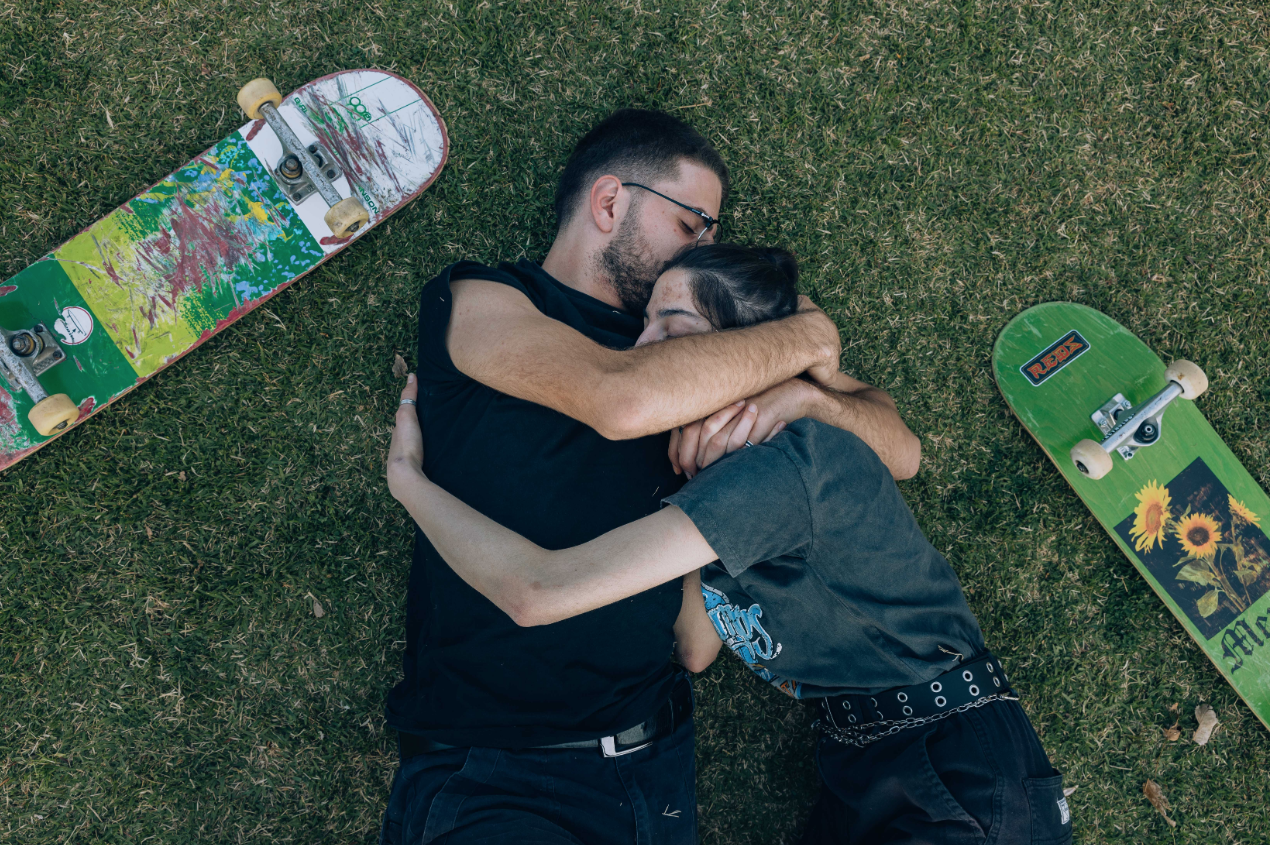 Photograph by Maen Hammad of two palestinian skate boarders hugging with their skate boards next to them