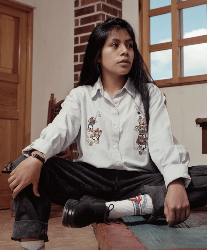 Photograph by Juan Brenner of a girl sat on a table in her bedroom in the Guatemalan Highlands