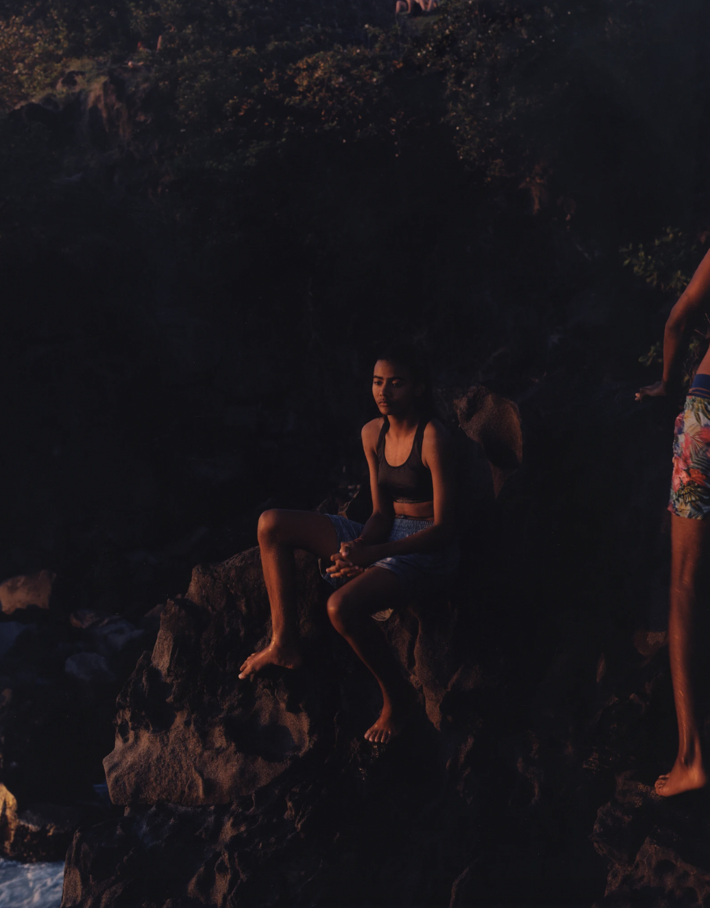 Photograph by Anaïs Makouke of a woman on a rock by the ocean on the island of Guadeloupe in the series Karukera