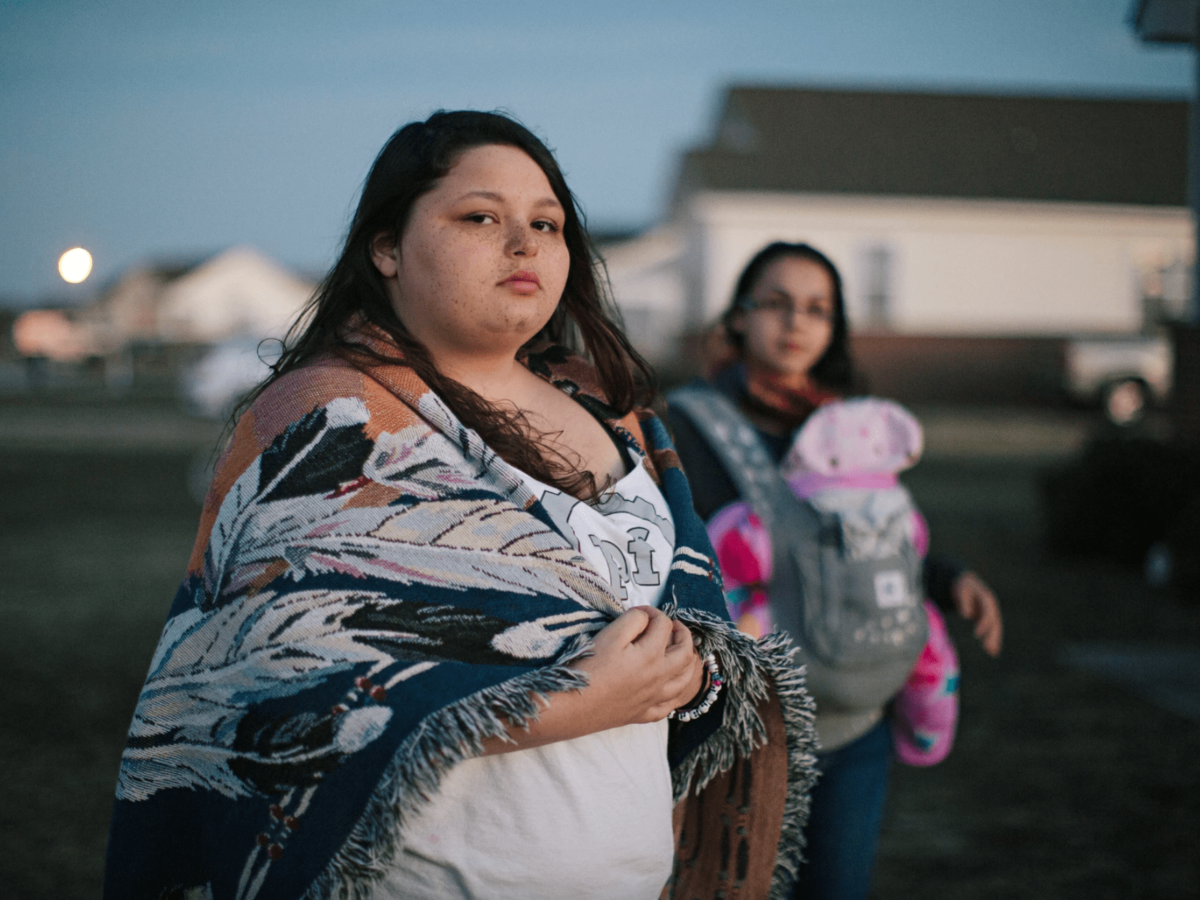 Photograph by Maria Sturm of two women of the lumbee tribe, one carrying a baby, outside a house