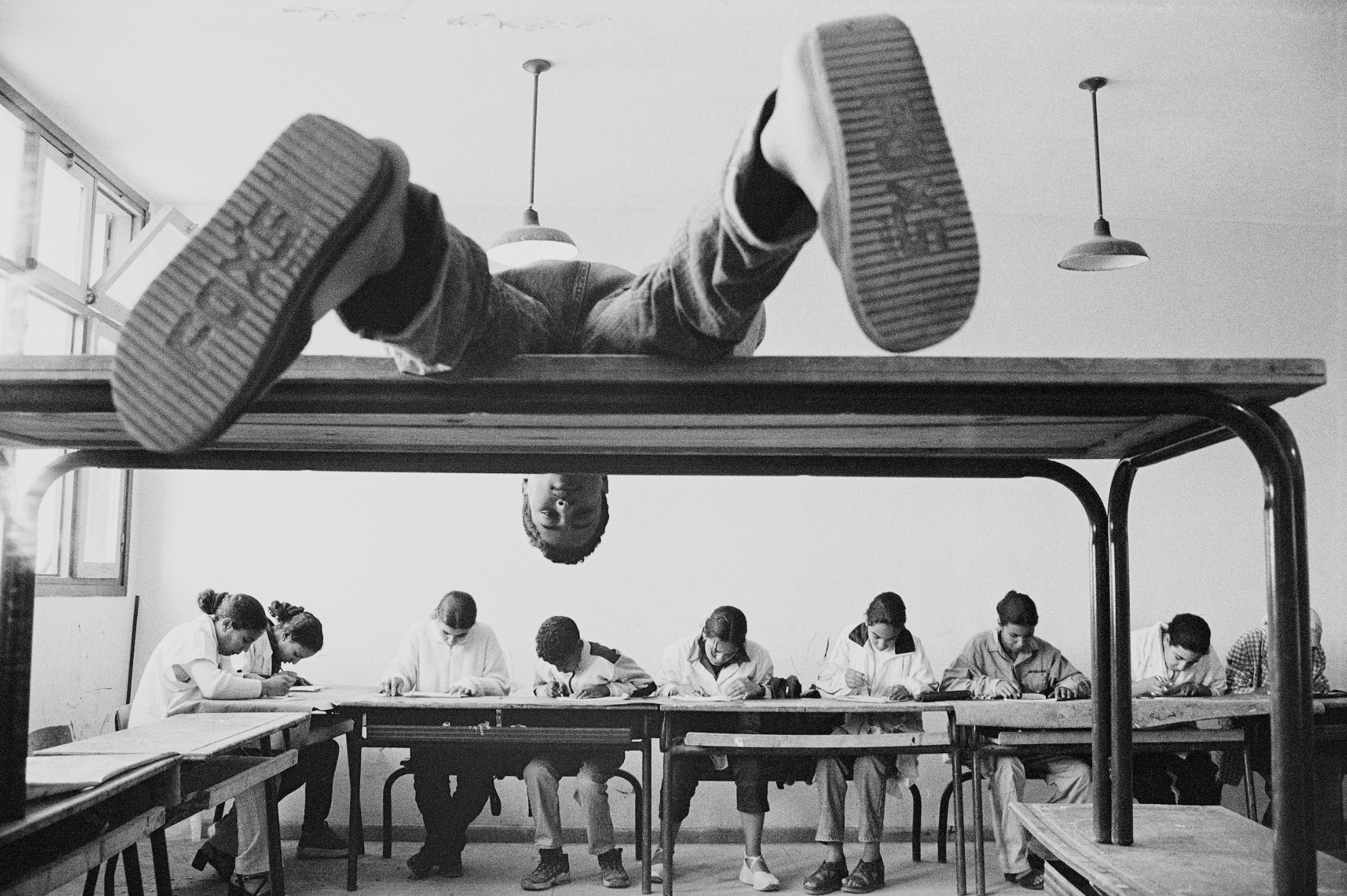 Photograph by Hicham Benohoud of a boy lying on a desk in a classroom in Marrakesh