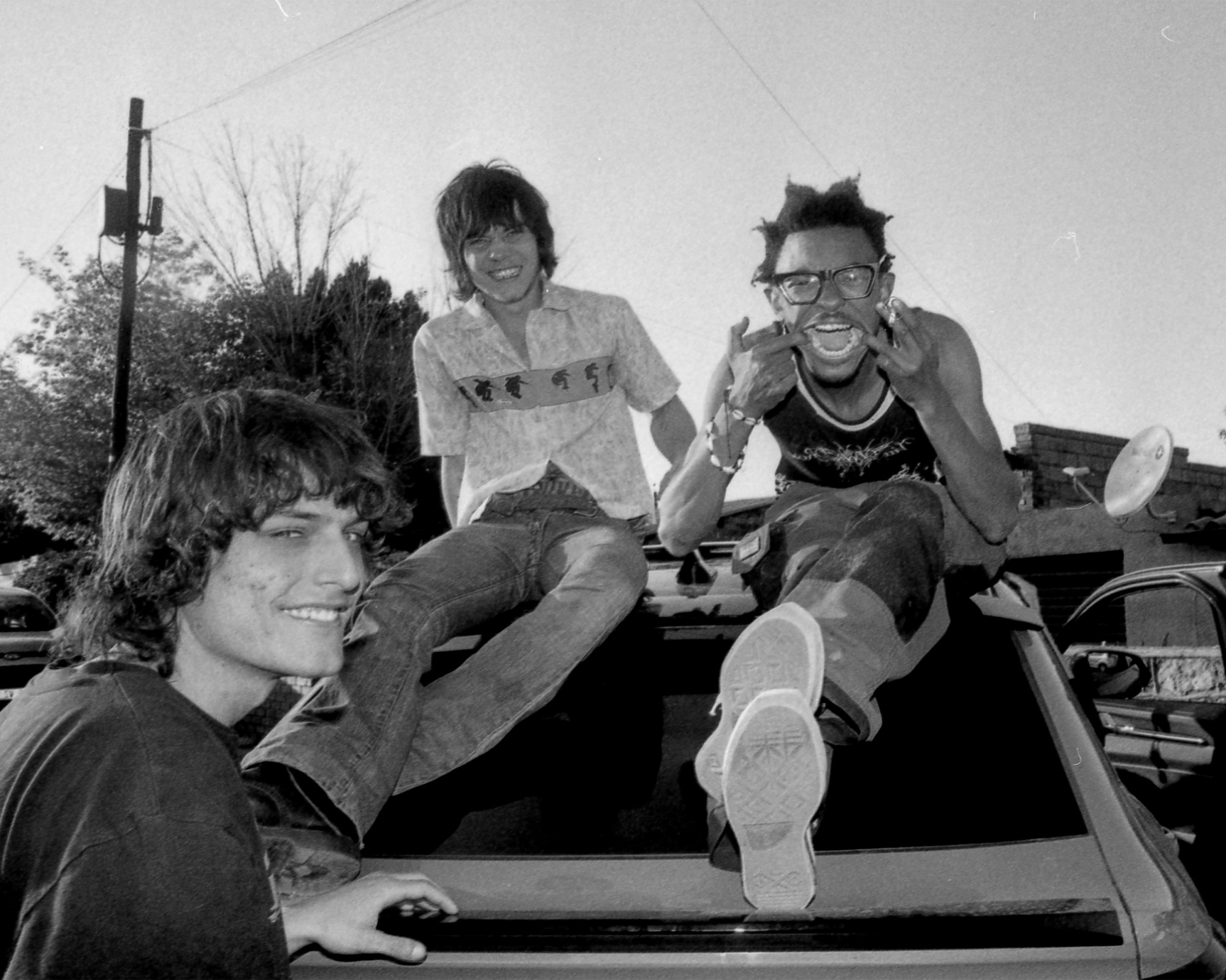 A black and white picture of punk young men smiling at the camera