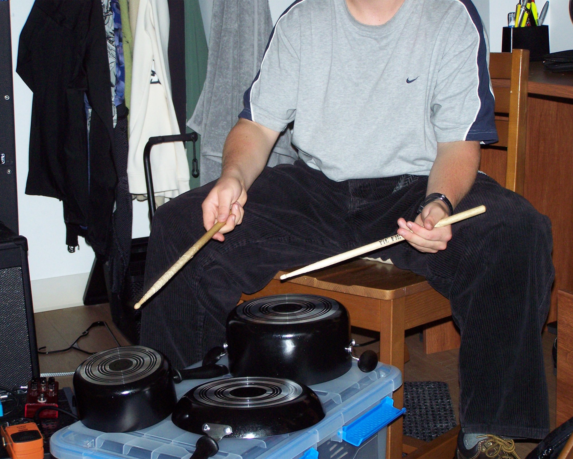 A photo of a person playing pots and pans with drumsticks.