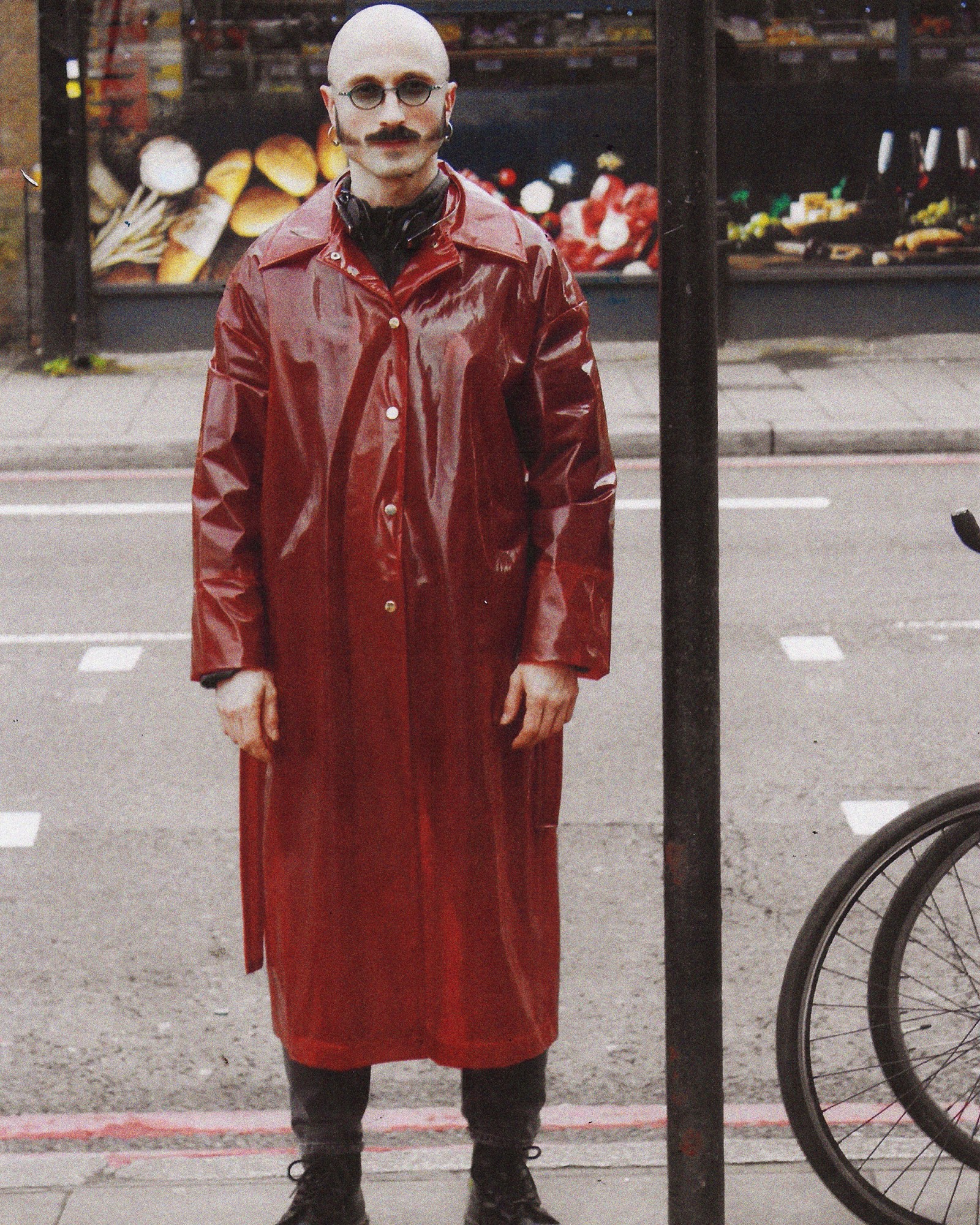 A full length photograph of a man wearing a red trench coat in London.