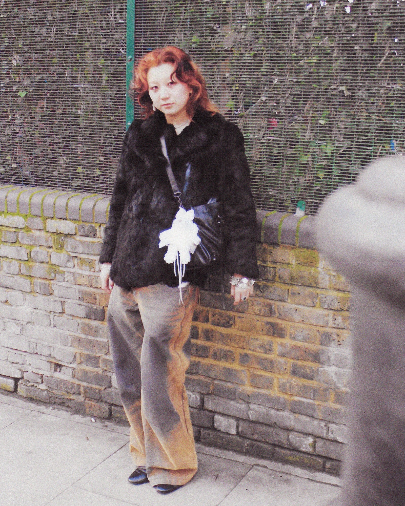 A full length photograph of a woman wearing a black fur coat and jeans in London.