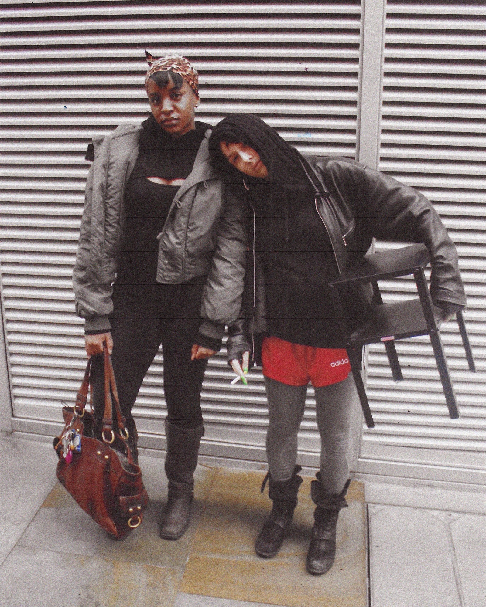 A full length photograph of two women in London, both wearing black outfits, one in a grey jacket, in London.