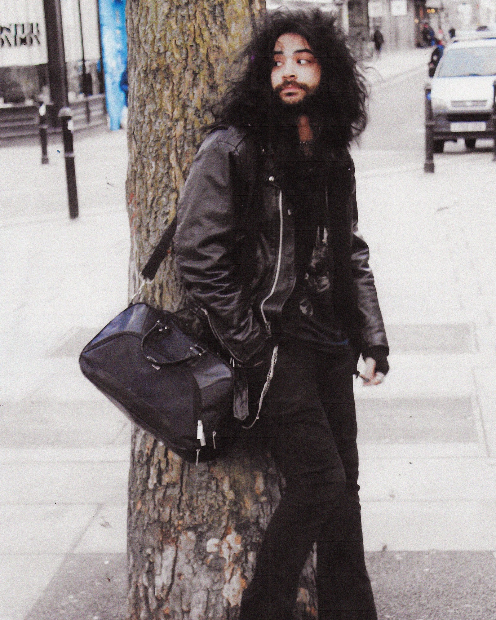 A full length photograph of a man wearing a black leather jacket and jeans in London.