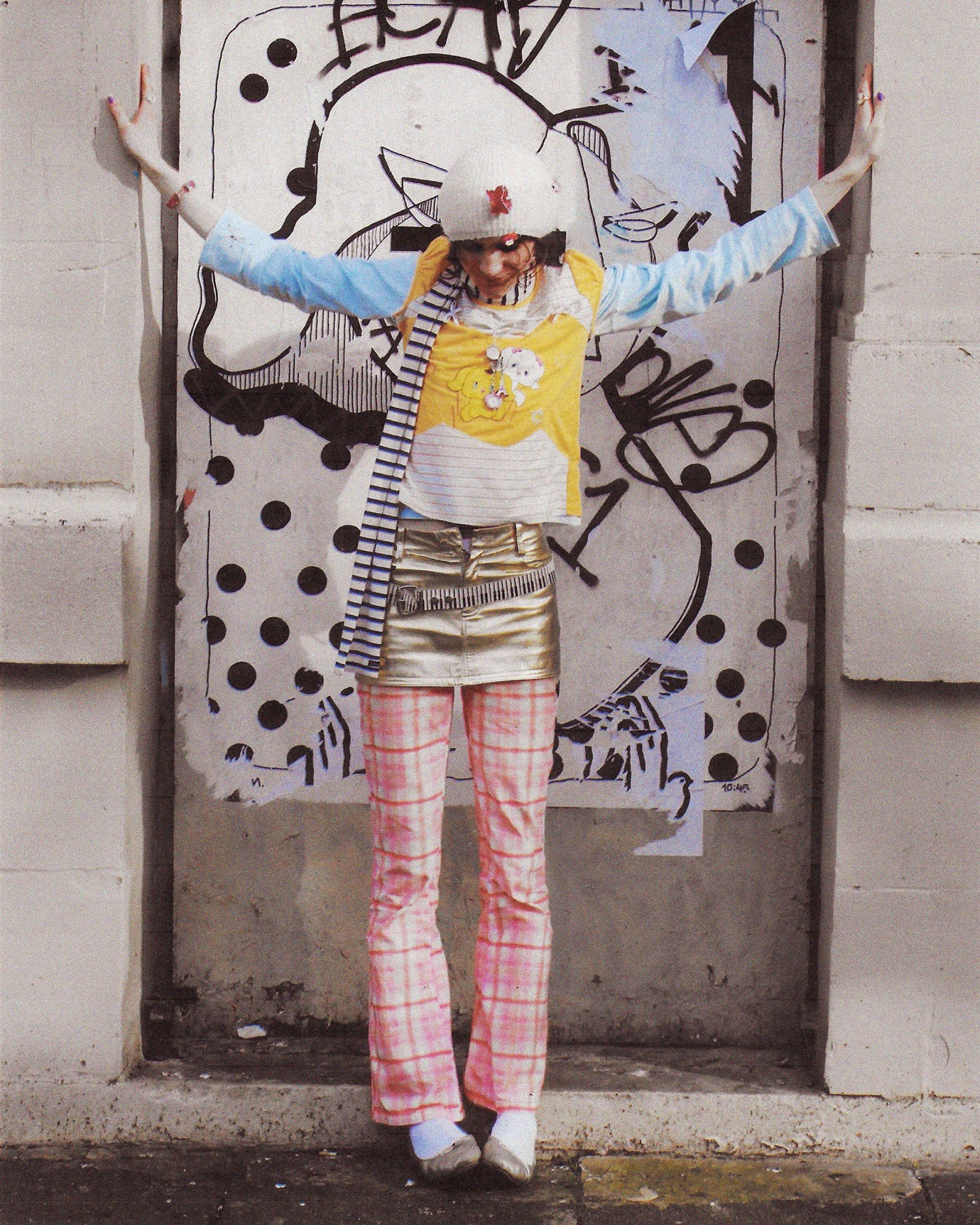 A full length photograph of a person in a blue top and pink trousers in London.