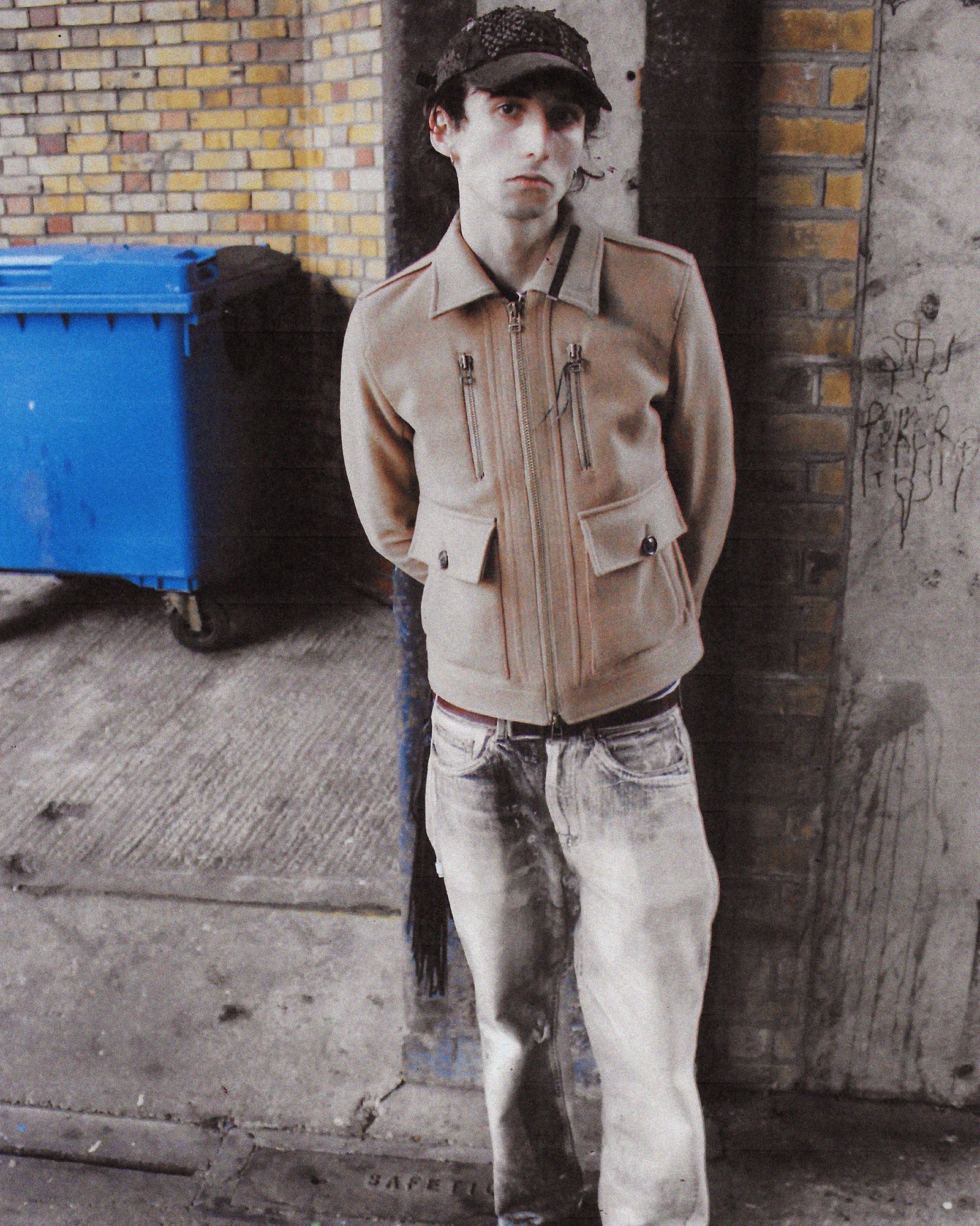 A full length photograph of a man wearing a beige jacket and jeans in London.