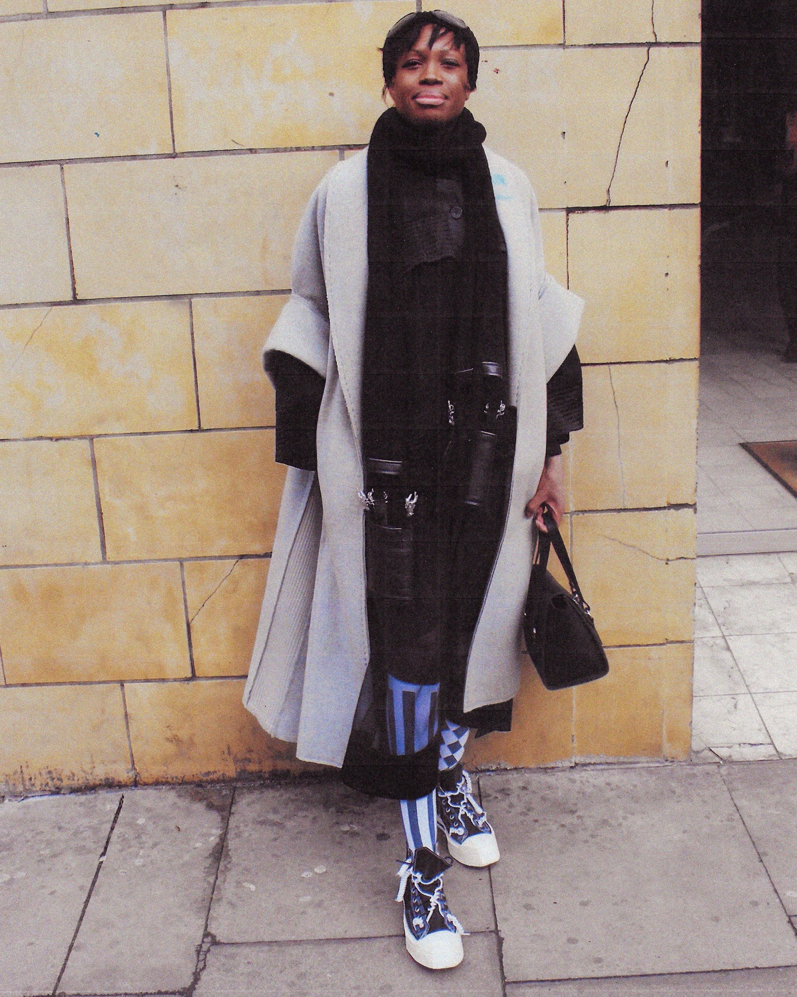 A full length photograph of a women wearing a grey trench coat in London.